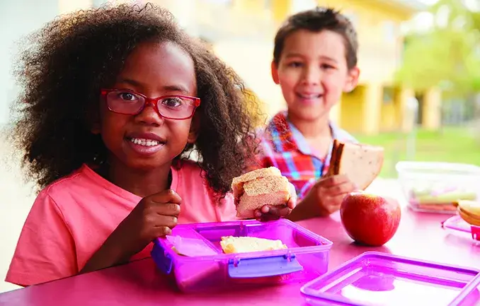 Children eating lunch at picnic table outdoors