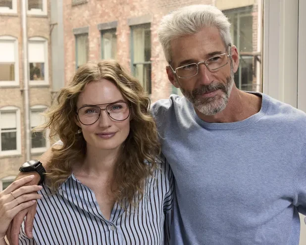 Male and female wearing glasses side by side in New York apartment