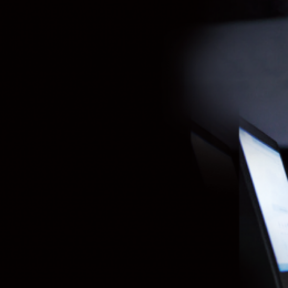 Woman typing on laptop in dark