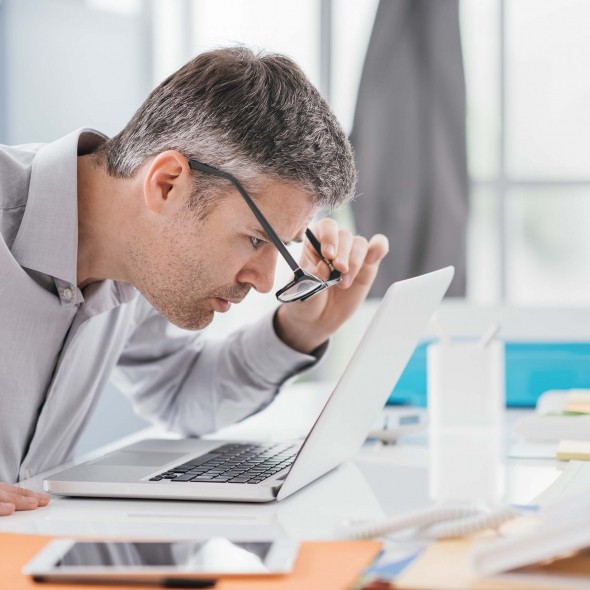 man squinting at computer screen