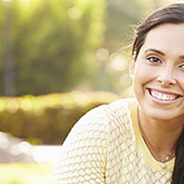 Brunette woman smiling and sitting in park