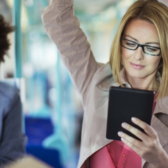 Woman in glasses reading tablet on bus