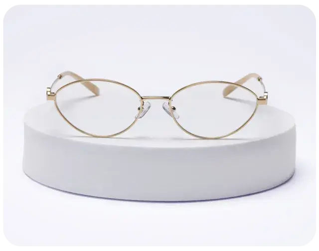 Gold metal eyeglasses on a white display stand