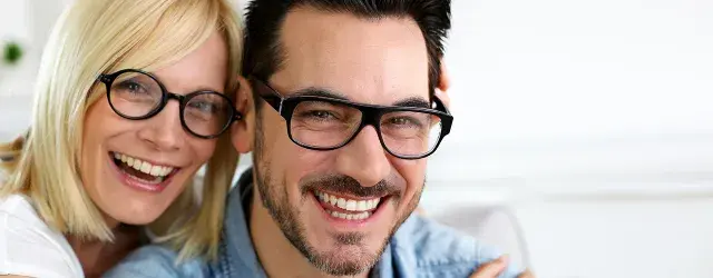 Male and female wearing glasses and smiling