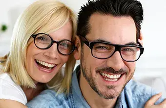 Male and female wearing glasses and smiling