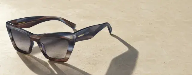 A close up of Ferragamo women's sunglasses on sand colored granite background