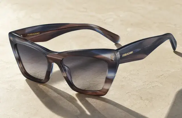 A close up of Ferragamo women's sunglasses on sand colored granite background
