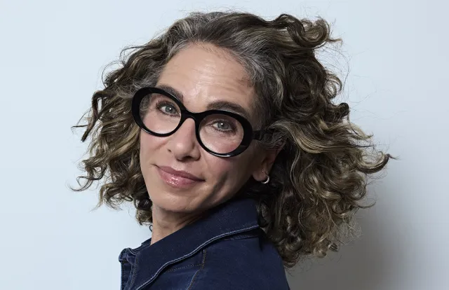 Woman wearing black glasses on gray background. 
