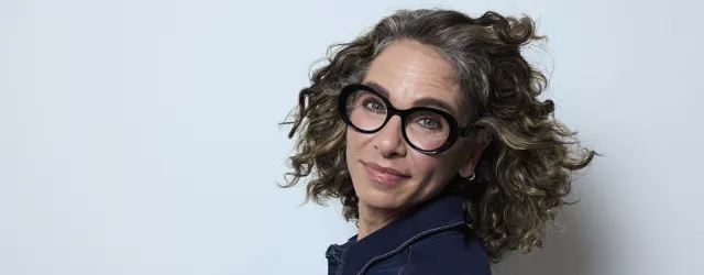 Woman wearing black glasses on gray background. 