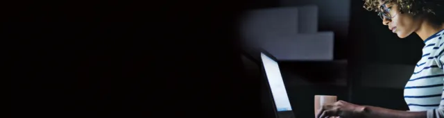 Woman typing on laptop in dark