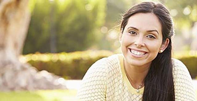 Brunette woman smiling and sitting in park