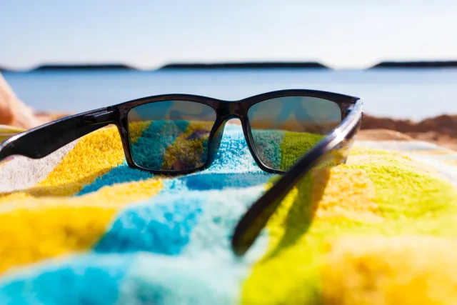 sunglasses on a beach towel in front of ocean