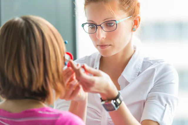 woman in glasses testing a persons eyes