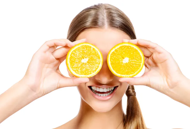 Girl holding oranges over eyes