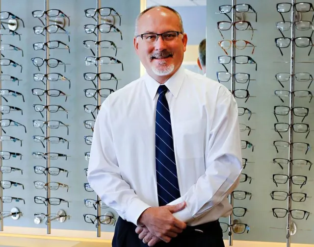 man smiling in front of glasses display
