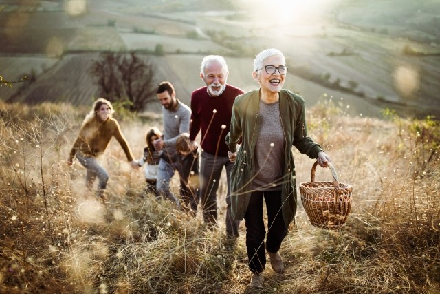 A family in glasses hiking up a hill with a picnic basket