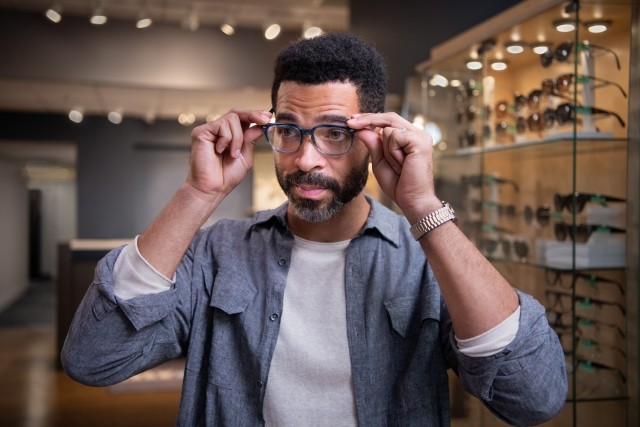 Man trying on eye frames in store