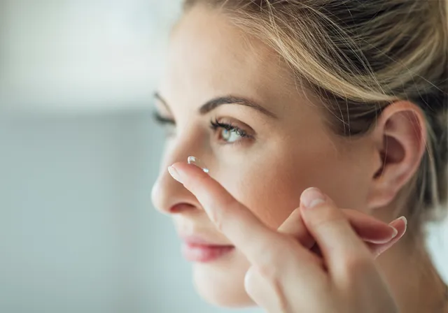 Woman putting in contact lenses