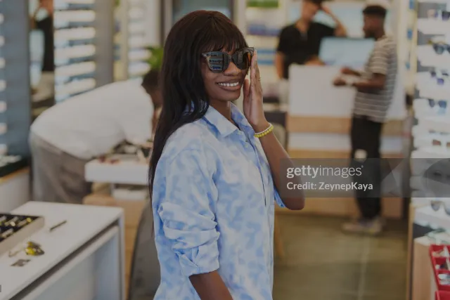 A customer trying on a sunglasses and smile at the camera