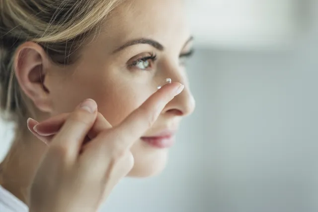 A close up shot of a woman putting on the contact lens