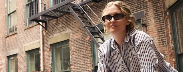 Female wearing tinted sunglasses on fire escape in brick apartment building