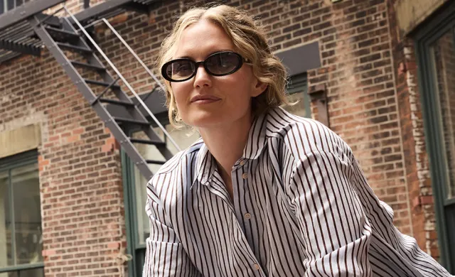 Female wearing tinted sunglasses on fire escape in brick apartment building